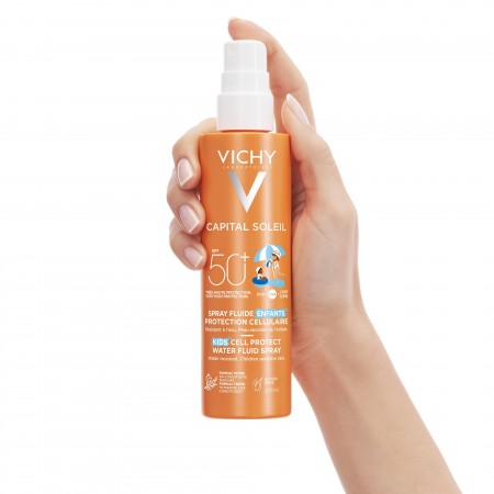Mano sosteniendo el envase del protector solar infantil en spray Vichy Capital Soleil